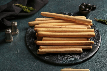 Slate board with tasty Italian Grissini on dark background