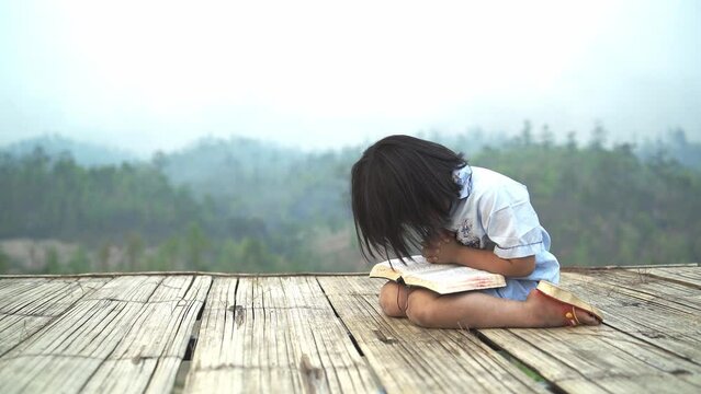 little girl pray and read Bible on mountain with copy space, christian concept.