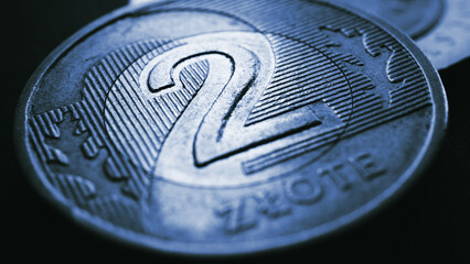 Translation: 2 zloty. Fragment of Polish two zloty coin close-up. National currency of Poland. Dark blue tinted illustration for news about economy or finance. Polish money. Macro