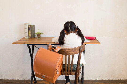 ランドセルの掛かった椅子に座り勉強する女の子