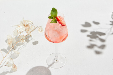 Strawberry alcoholic cocktail on white background with shadows. Summer drink strawberry spritz with empty place. Strawberry mocktail in minimal style. Pink cocktail in summer menu on light background. - obrazy, fototapety, plakaty