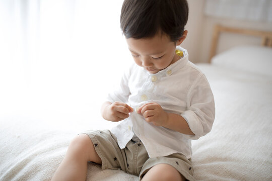 洋服のボタンをとめている男の子