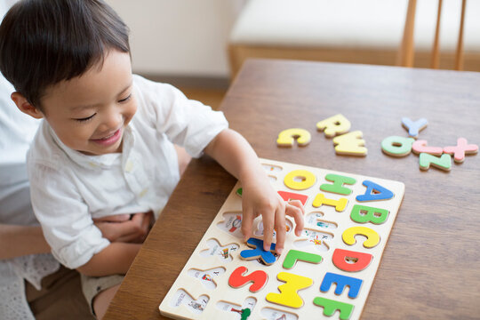 英語の知育玩具で英語の学習をする男の子とそれを手伝う母親