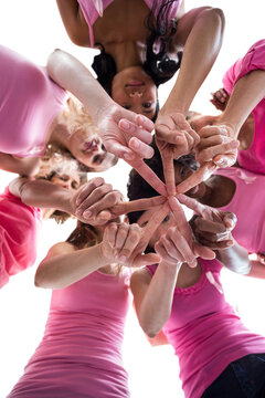 Directly below shot of females in pink outfits touching fingers for breast cancer awareness