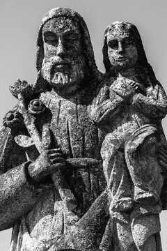 Saint Joseph with little Jesus Christ. Very ancient stone statue. White and black vertical image.