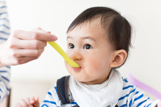母親に離乳食を食べさせてもらう赤ちゃん