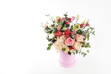Beautiful bouquet in festive round box on white table.Pink box.Variety of flowers in the bouquet.Gift for a holiday, birthday, wedding, Mother's Day, Valentine's Day, Women's Day. Isolated object.
