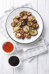 Homemade fresh fried shiitake mushrooms with green onions close-up on a white plate. Vertical top view from above
