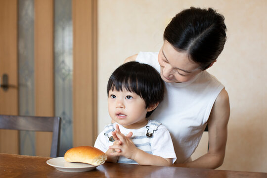 母親の膝の上でパンを食べる子ども