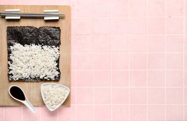 Nori with rice and sauce on pink tile background