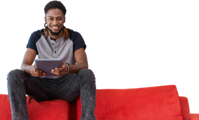 Smiling male college student holding digital tablet while sitting on sofa