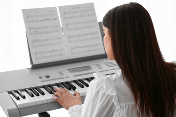 Fototapeta na wymiar Young female musician playing synthesizer at home