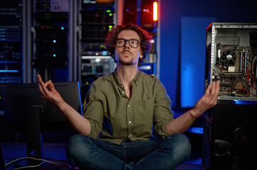 Pensive technician meditating in server room at modern data center - obrazy, fototapety, plakaty