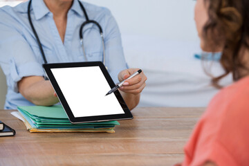 Doctor discussing with patient over digital tablet