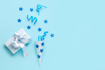 Party cone with serpentine, stars and gift on blue background