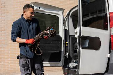 Hispanic male craftsman electrician taking tools out of his professional van - solar panel...
