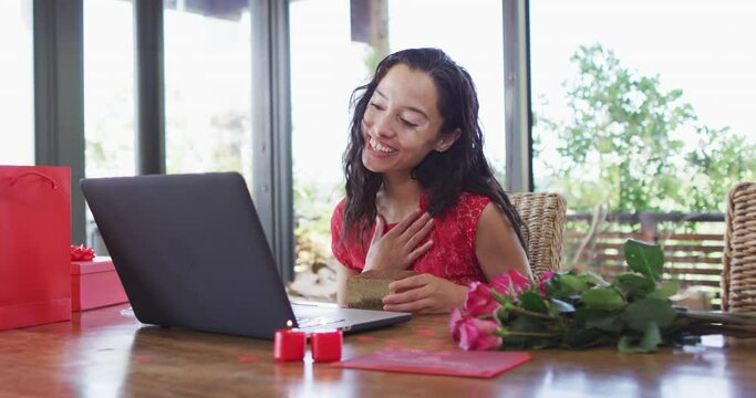 Happy biracial woman with vitiligo making valentine's day video call on laptop, sending kisses
