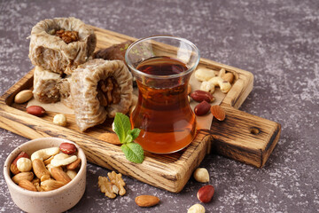 Wooden board with glass of tea and Turkish delight on grey background