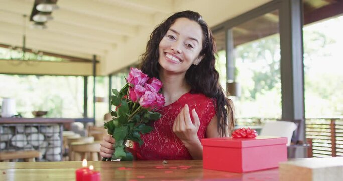 Happy biracial woman with roses making valentine's day video call, sending kisses