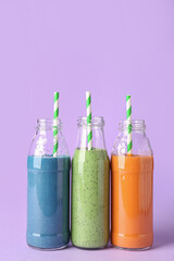 Fototapeta na wymiar Glass bottles of different tasty smoothie with straws on violet background