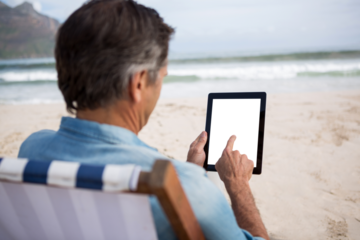 Man using digital tablet at beach