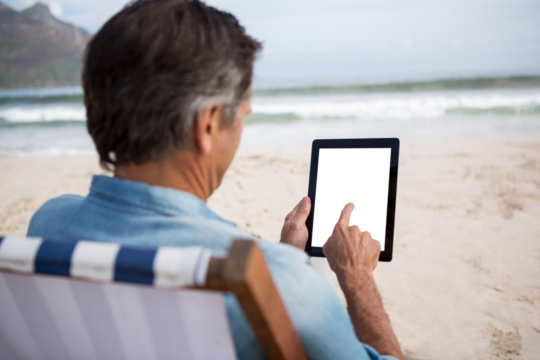 Man using digital tablet at beach