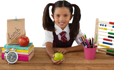 Schoolgirl holding Granny Smith apple at desk