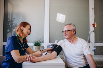 Female professional doctor examining elderly old male patient measuring high low arterial blood...