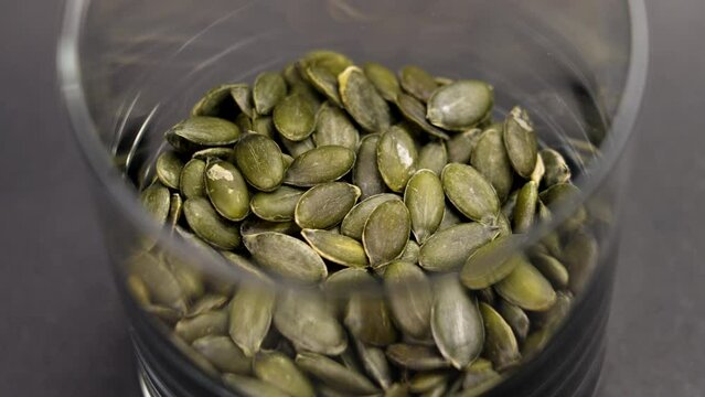 Raw peeled green pumpkin seeds in a glass close up. Rotation.