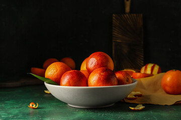 Bowl with tasty blood oranges on green table
