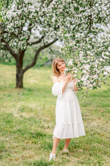 Fototapeta na wymiar beautiful woman in a white dress walks in the spring garden