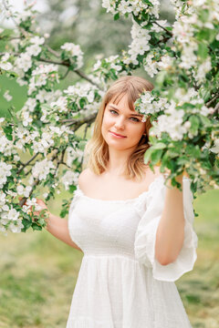 Portrait of pretty blong girl posing against the spring flowers