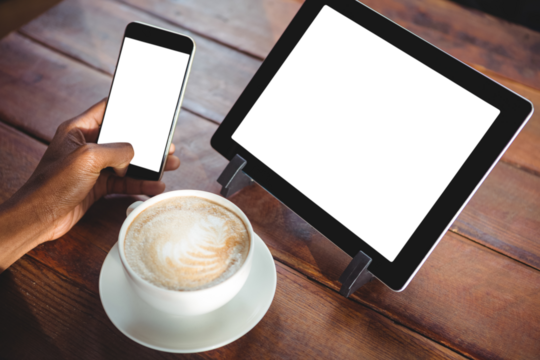 Woman using mobile phone by coffee and digital tablet