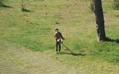 Top view of a man mowing grass with a trimmer.