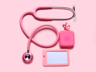 Stethoscope, pills organizer and badge on pink background