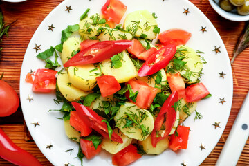 Plate of tasty Potato Salad with vegetables on wooden background, closeup