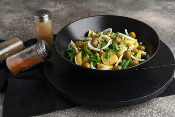 Bowl of tasty Potato Salad with vegetables on grunge background