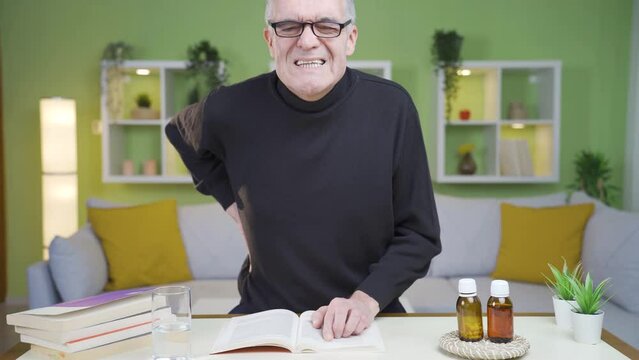 Low back pain of old man getting up from table.
The old man suddenly gets up from the table and has pain in his lower back.
