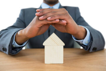 Businessman protecting house model with hands