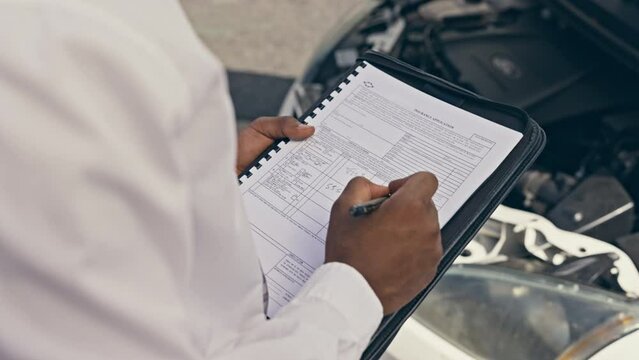 Car service, checklist and man hands writing for mechanic and transport quality control job. Professional, engine check and garage safety report of a maintenance employee with auto repair inspection