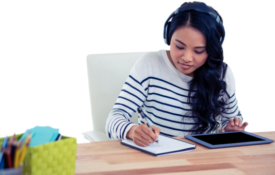 Smiling Asian woman with headphones writing on notepad