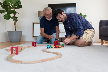 Happy adult family. Senior mature father and adult son playing car wood toy with happy and smiling...