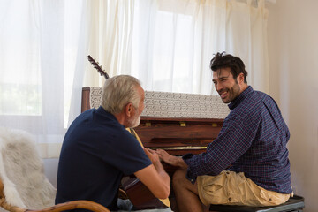 Happy Adult family. Senior Father playing guitar and Adult Son playing Piano with happy and smiling...