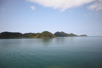 Front view in bright blue morning sky with clear white clouds and deep blue ocean in daytime gives calm and relaxing idea for cool background and copy space above the boat.