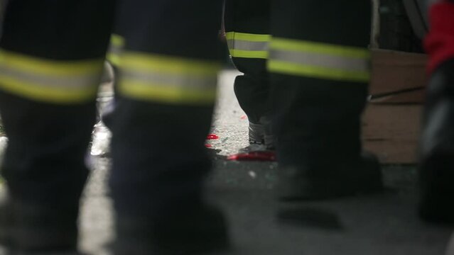 Shattered glass falling on the ground next to the firefighters legs in slow motion