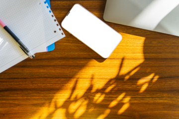 Wood office desk table with laptop, notebook and pen and cell phone