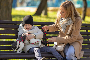 Sitting with cute cat. Mother and cute little son is together outdoors at daytime with a domestic cat