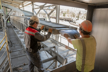 Loading and unloading works, manual labor. A pair of movers stand by a conveyor belt waiting for...