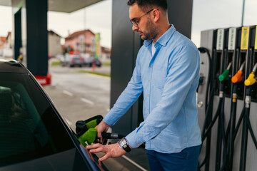 A man fills his car with fuel before going to work at a self-service gas station - obrazy, fototapety, plakaty