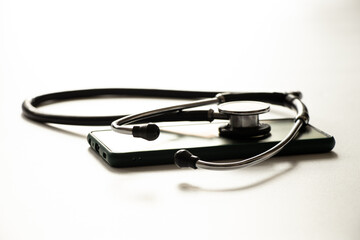 The stethoscope lies on a smartphone on a white background, online doctor, doctor call, medicine